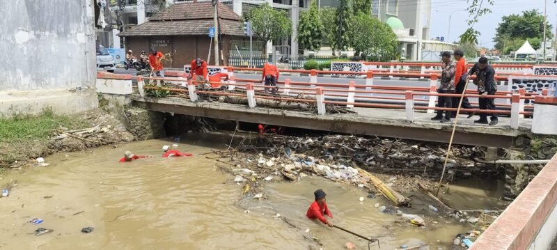 Petugas Dinas Lingkungan Hidup (DLH) Kendal bersama tim terkait membersihkan tumpukan sampah yang menyumbat aliran Sungai Kendal di bawah jembatan jalur Pantura, Selasa (30/12/2025). (Istimewa/Wawasannews)