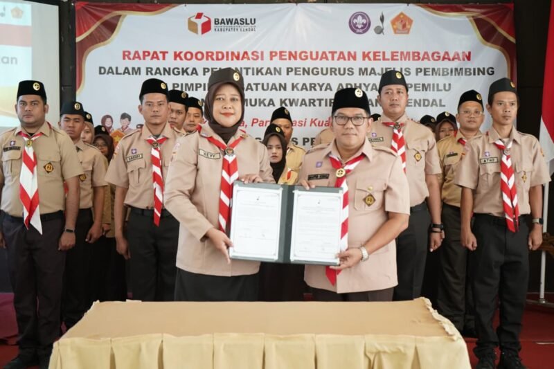 Ketua Bawaslu Kendal Hevy Indah Oktaria (kiri) bersama Ketua Kwarcab Kendal Kak Mahfud Sodiq (kanan) menunjukkan dokumen kerja sama usai pelantikan Majelis Pembimbing dan Pimpinan Saka Adhyasta Pemilu Kendal di Tirto Arum Kendal, Rabu (3/12/2025). Dok pribadi. (Wawasannews)