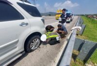 Personel Satgas Kamseltibcarlantas Polres Kendal membantu pemudik mengganti ban kendaraan yang pecah di ruas Tol Batang–Semarang KM 387A, Sabtu (14/3/2026). Foto : Wawasannews.com