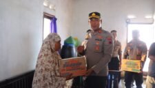 Kapolres Kendal AKBP Hendry Susanto Sianipar menyerahkan bantuan sembako kepada Siti Rokhanah, warga Kelurahan Balok yang masih bertahan tinggal di kawasan terdampak banjir rob, saat kegiatan Bakti Sosial Hari Bhayangkara ke-80, Senin (15/6/2026). (Istimewa/Wawasannes)